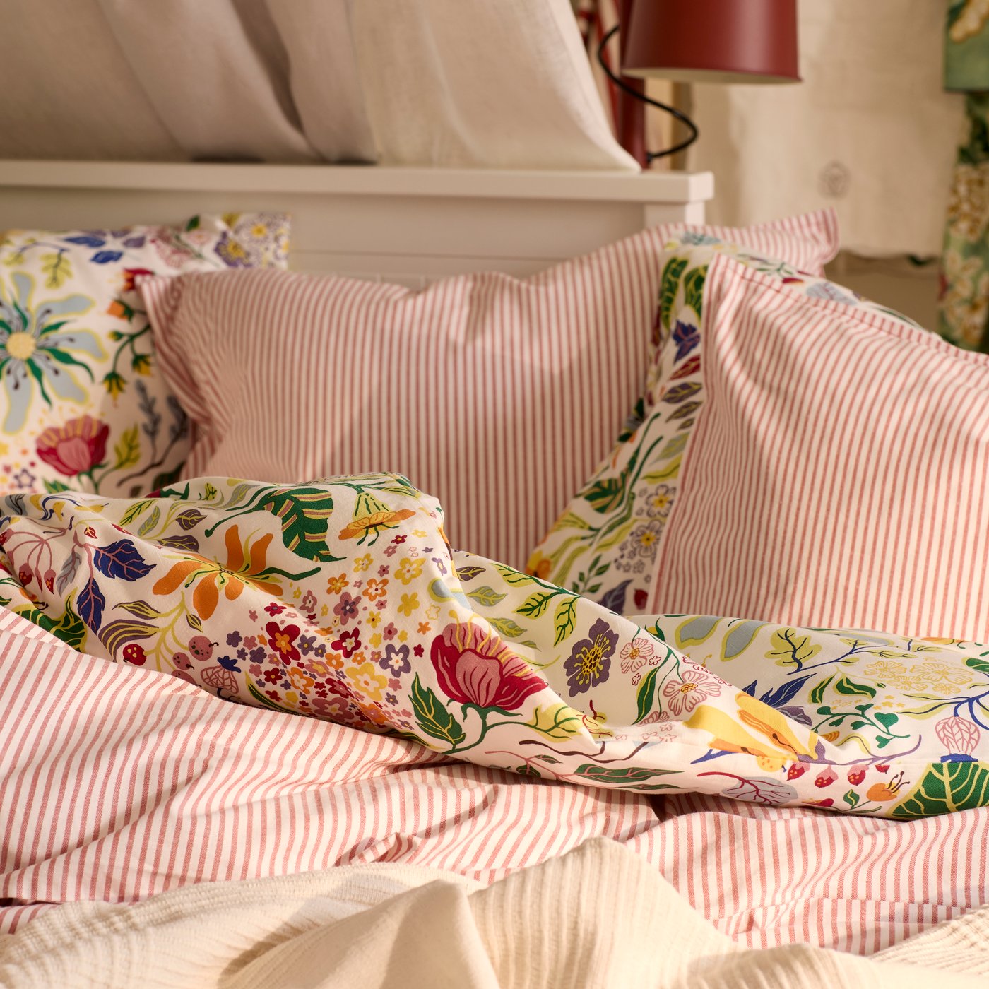 A close-up of a HEMNES day-bed with a mix of bedlinen; the striped SOLFIBBLA and the floral patterned BRUDKRUSBÄR.