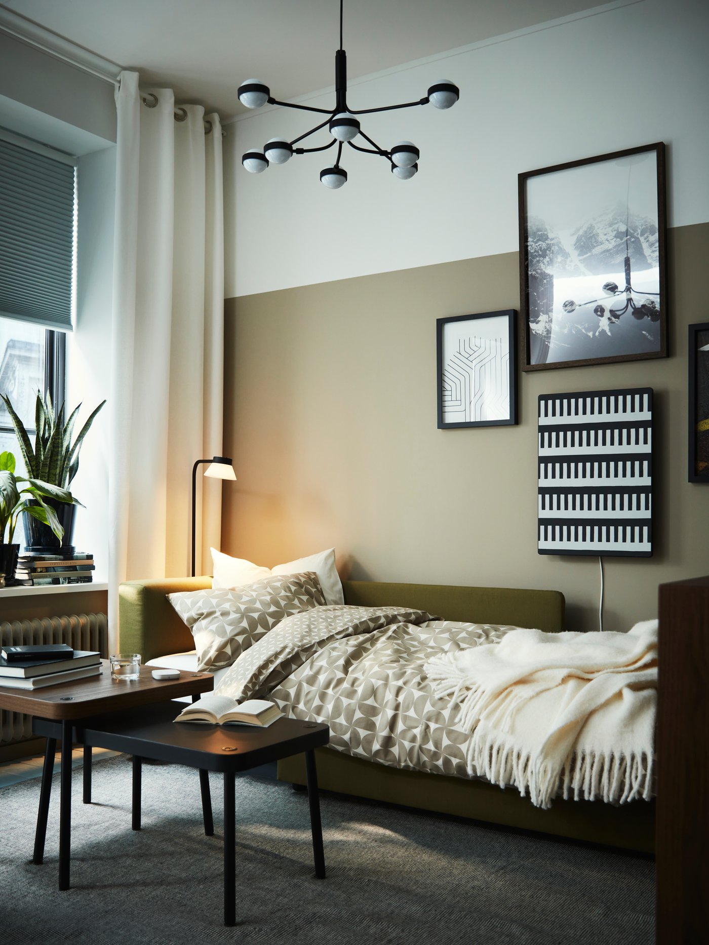 A yellow-green SKÖNABÄCK 2-seat sofa-bed, used as a bed, with ÄNGSNEJLIKA bed linen and an off-white KLIPPOXEL throw.