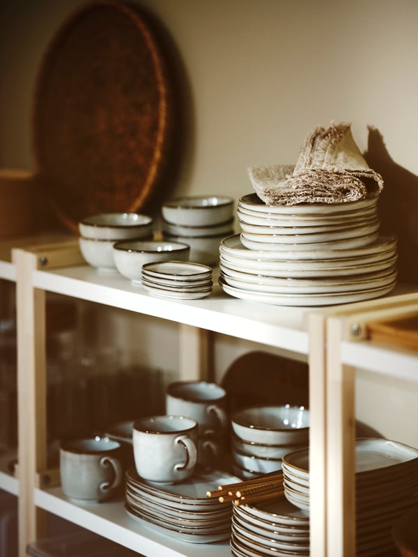 On the EKENABBEN shelf element the tableware of the series GLADELIG is stacked to a potluck buffet.