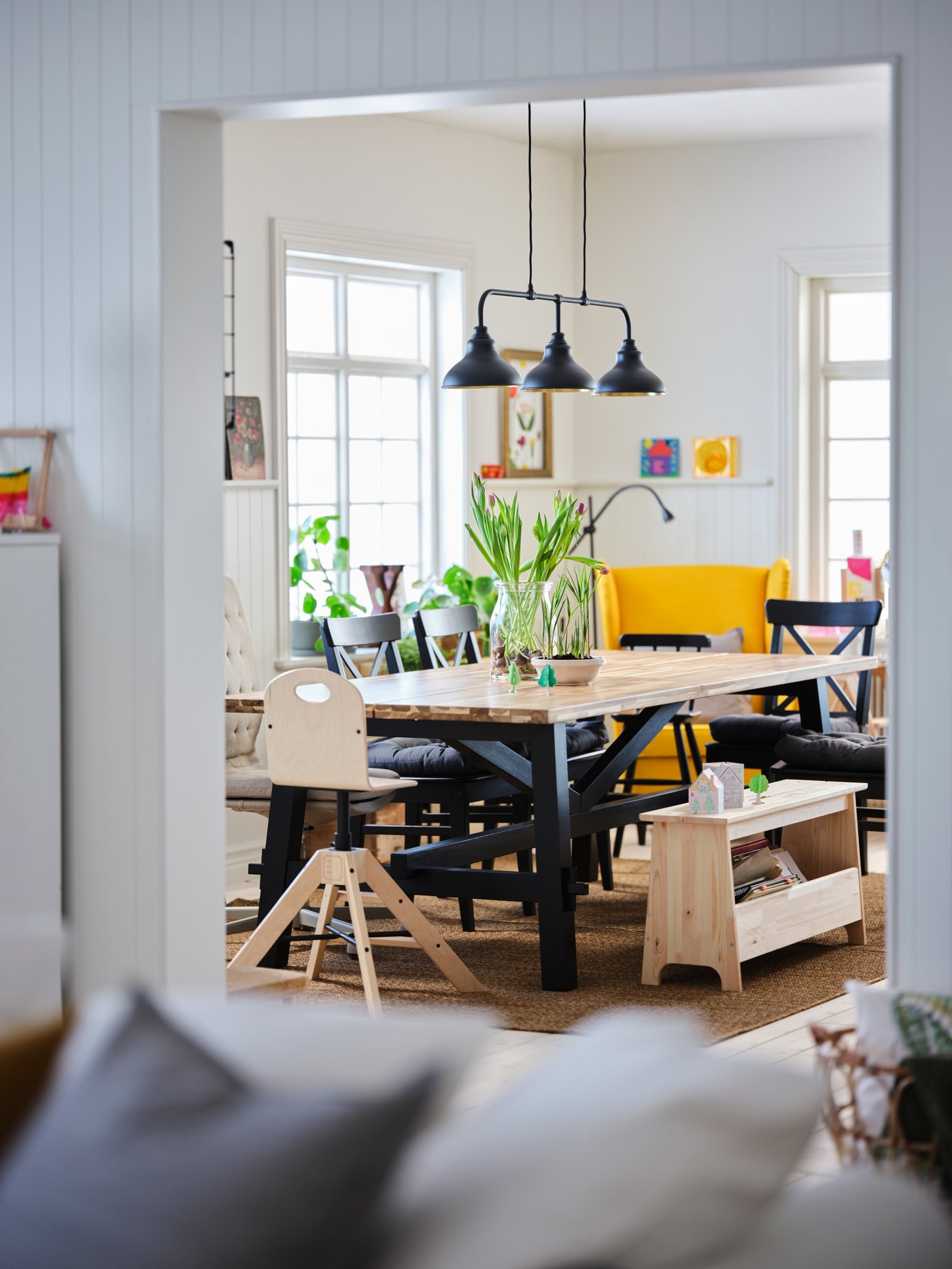 Blick in ein Familienesszimmer mit einem großen Esstisch aus Holz, einer Sitzbank aus Holz mit Stauraum und vielen Stühlen rundherum.