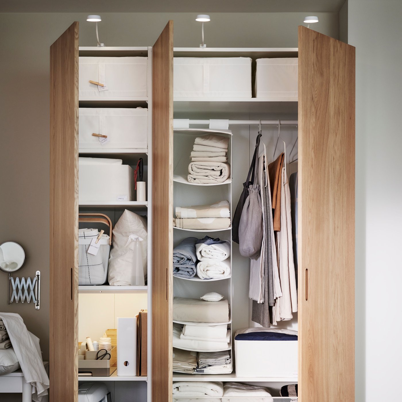 Ein weisser/eichenfarbener PAX/TONSTAD-Kleiderschrank mit beiden Türen geöffnet, in dem SKUBB-Aufbewahrungsboxen und andere Gegenstände auf den Regalen zu sehen sind.