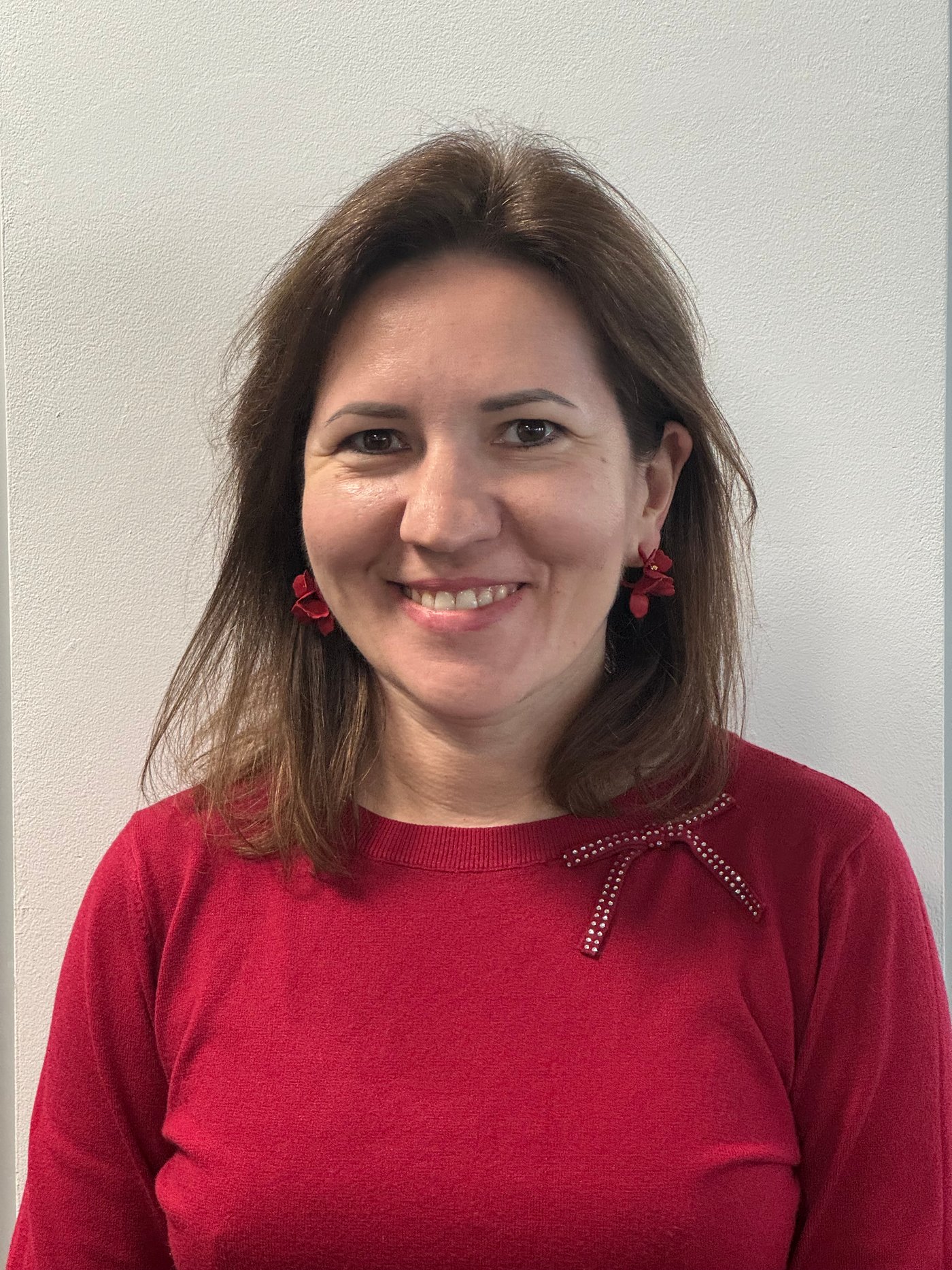 Olena lächelt in einem roten Pullover in die Kamera.