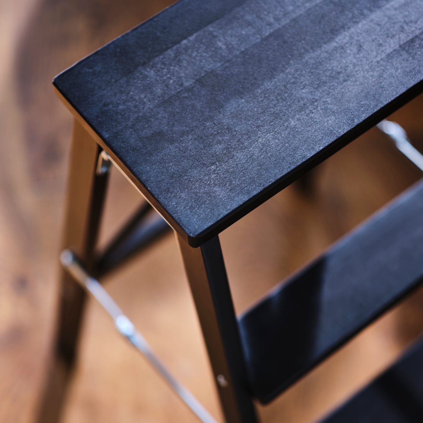 A black BEKVÄM stepladder with 3 steps on a wooden floor.