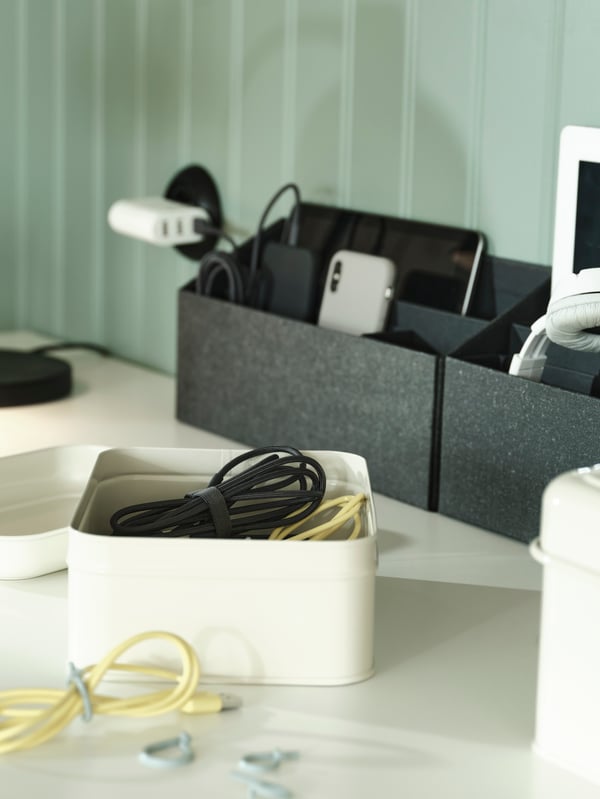 A close-up of small boxes and desk accessories that keep cables and tech stuff organised and nicely hidden.