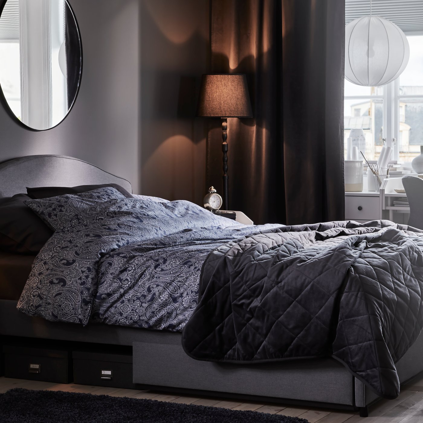Un dormitorio con una cama HAUGA tapizada en gris Vissle con cajones tapizados y vestida con ropa de cama JÄTTEVALLMO.