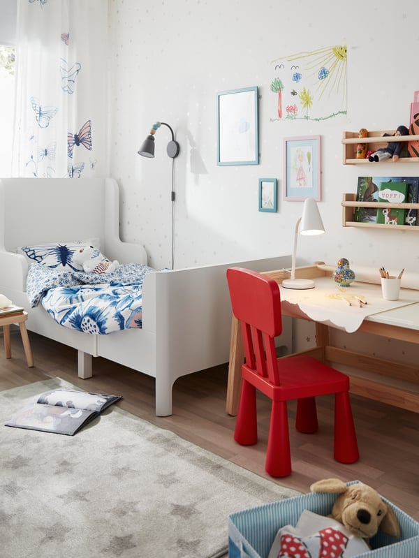 Una habitación infantil con una cama extensible y en los pies un escritorio FLISAT con una silla MAMMUT.