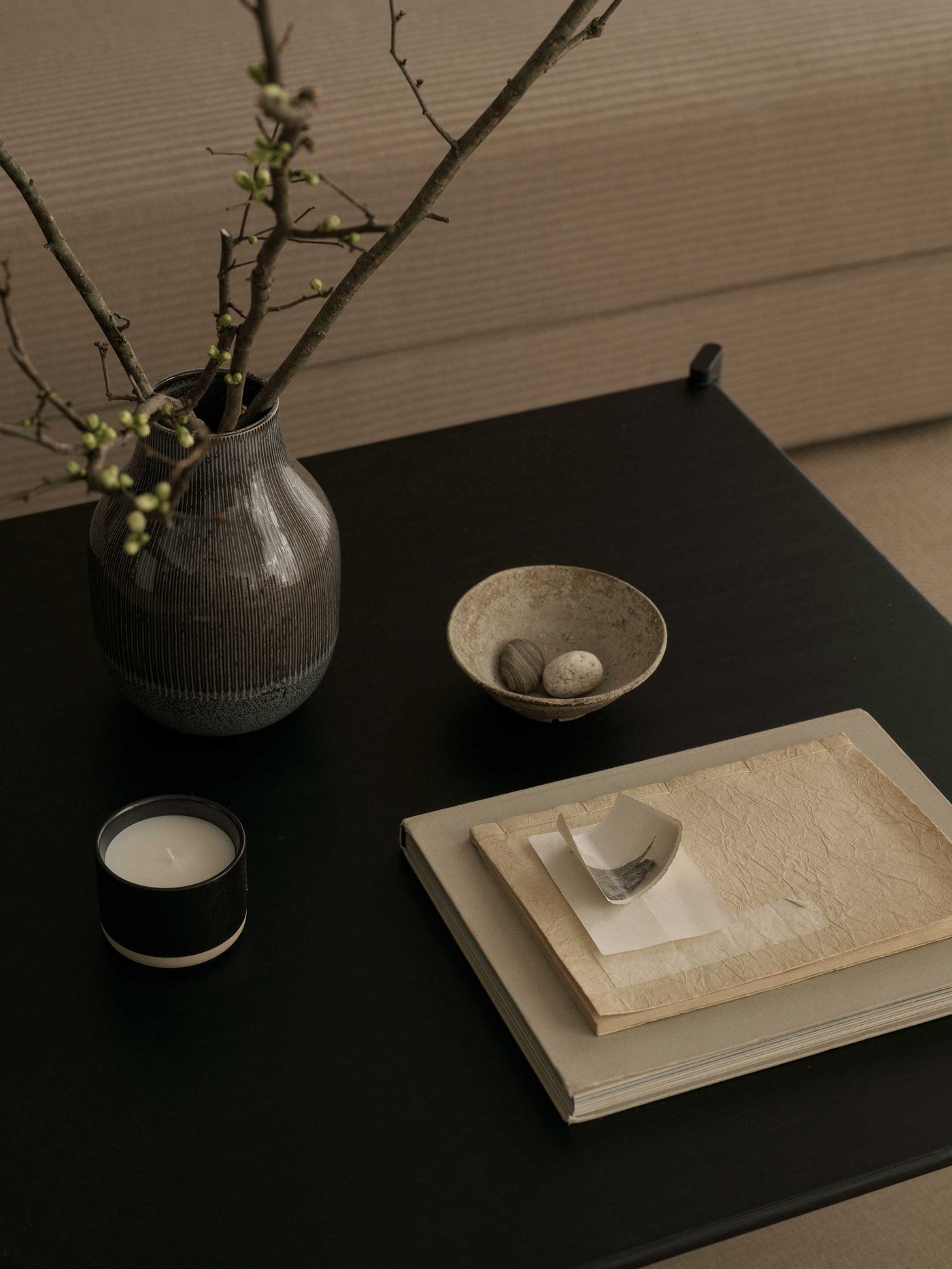 黒いテーブルの上に和紙でできた本、陶器製の花瓶や小皿、キャンドルが置いてある。