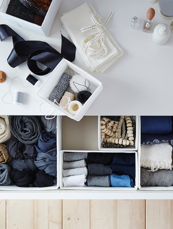 In de open lade van een ladekast zitten kleding en accessoires netjes opgeborgen in SKUBB dozen.