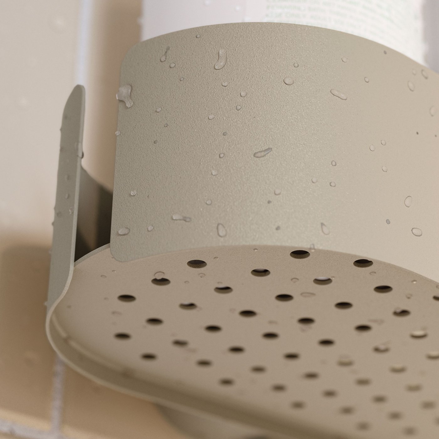 Primo piano dal basso di una mensolina per doccia FLORSJÖN grigio-beige fissata a una parete piastrellata, con i piccoli fori di drenaggio ben visibili.