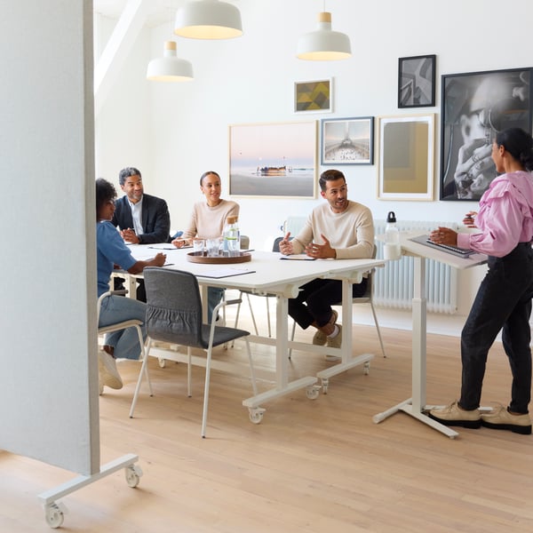 Plan d'ensemble de personnes assises à une table blanche dans une salle de réunion.