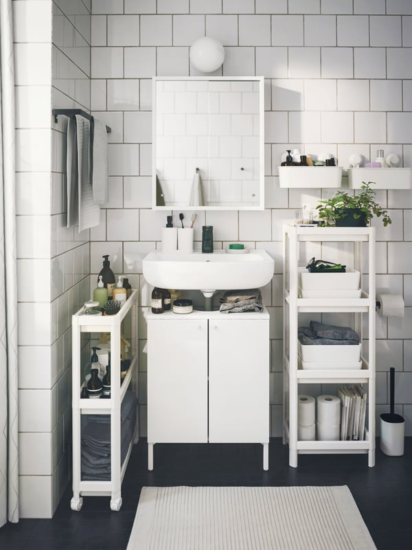Baño con carrito VESKEN y mueble de almacenamiento VESKEN, ambos color blanco.