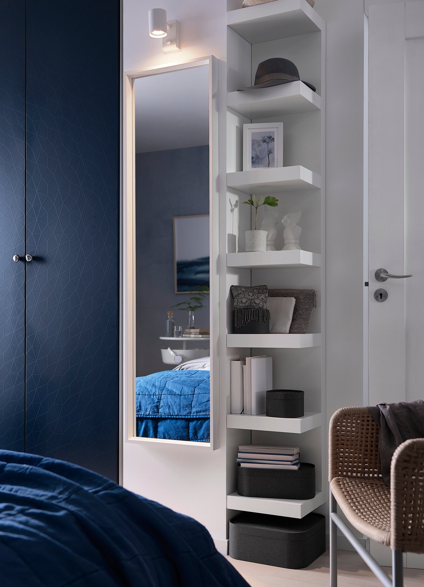 A white LACK wall shelf mounted on the wall next to a white NISSEDAL mirror in the bedroom.