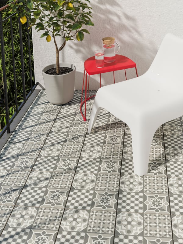 Balkon s dezeniranim MÄLLSTEN podnim oblogama, limun u saksiji i bela plastična stolica.