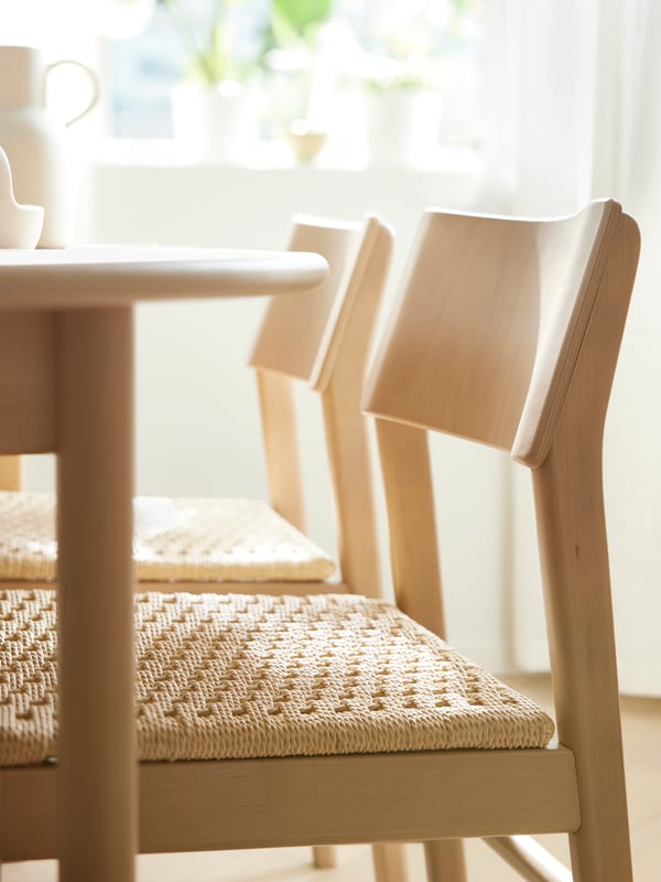 Two light beech SKANSNÄS chairs stand at a light beech/veneer SKANSNÄS round extendable table in a sunny dining room.