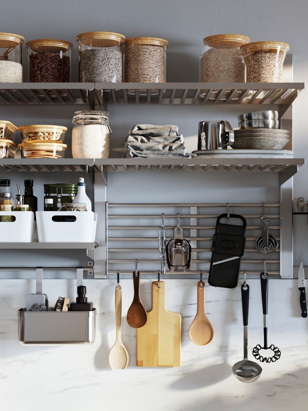 Stainless steel KUNGSFORS suspension rail with a shelf and wall grid holding glass jars with lids and white VARIERA boxes.