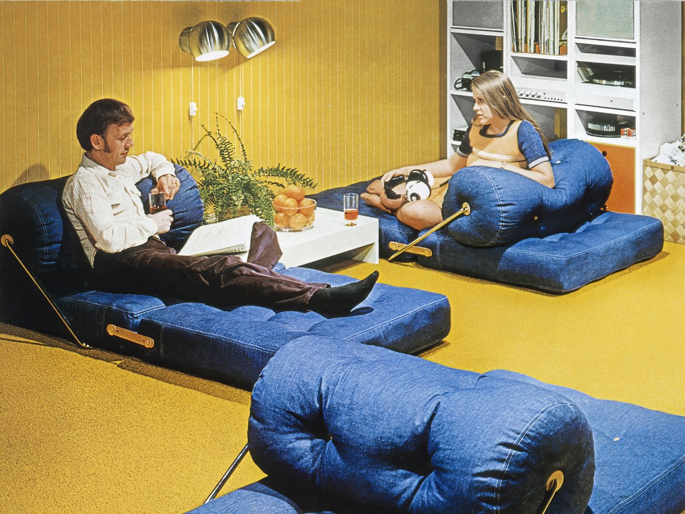 Naslovna fotografija IKEA kataloga iz 1973. na kojoj se vidi par zavaljen u dve TAJT fotelje bez rukohvata u prostoriji sa žutim tepihom.