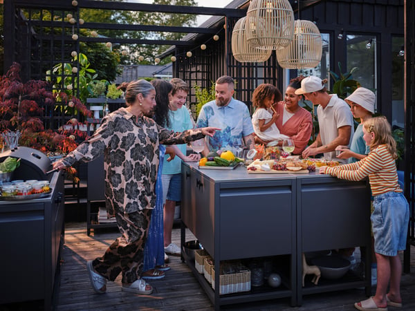 IKEA BÅTSKÄR outdoor kitchen units sorrounded by people having a meal outside.