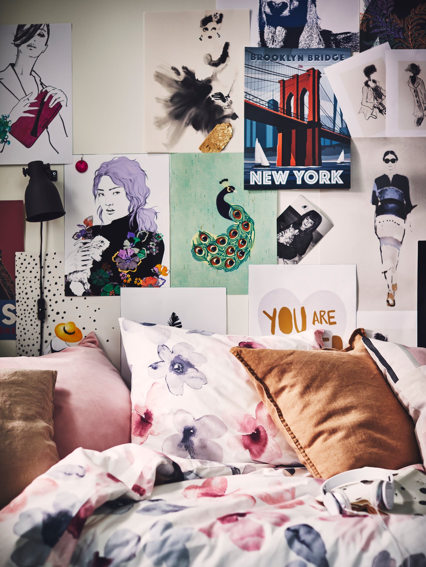 A bed dressed in a LAPPNYCKLAR duvet cover and pillowcase, with a wall covered in illustrations and BILD posters.