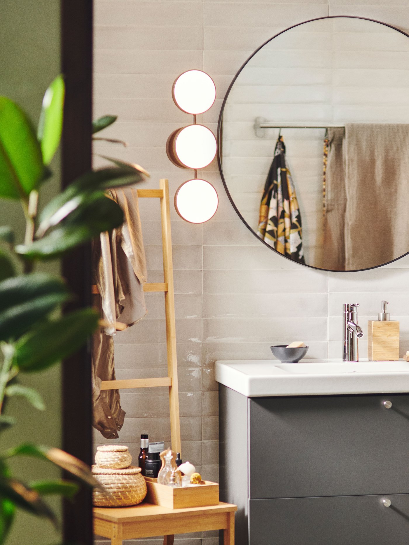 Un aplique LED KABOMBA cromado/brillante regulable al costado de un espejo para baño LINDBYN