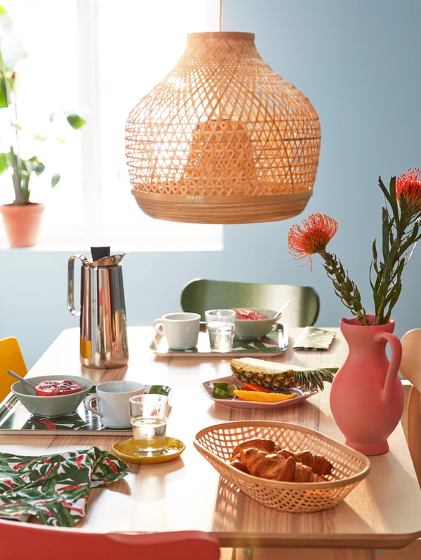 Un comedor con una mesa con productos de la serie IKEA 365+, LISABO y METALLISK. Sobre la mesa una lampara de la serie MISTERHULT.