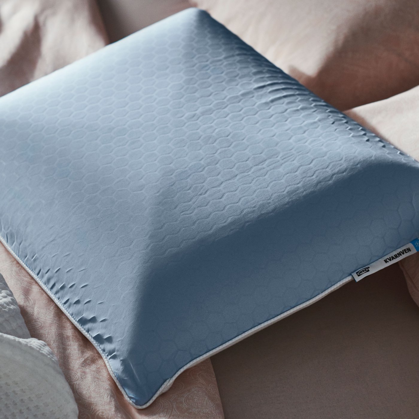 A KVARNVEN egonomic pillow with no pillowcase on it sitting on top of a slightly ruffled duvet.