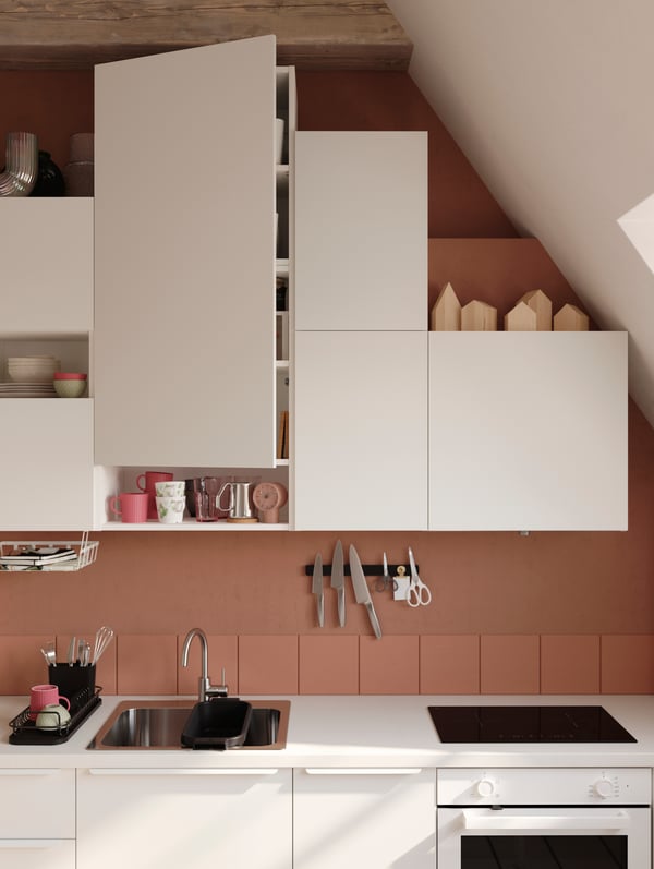 White VALLSTENA with open and closed storage, built around a sloped ceiling, with terracotta-colored walls.