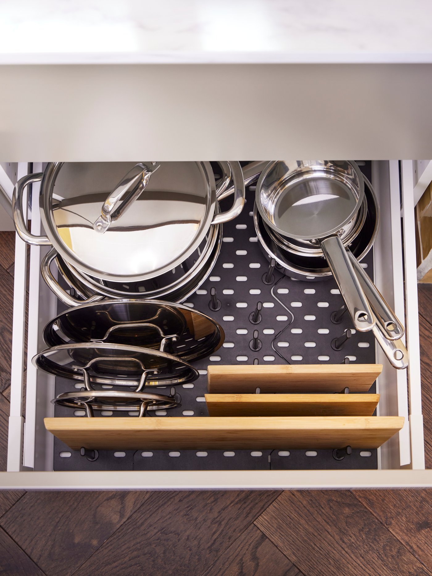 An UPPDATERA pegboard drawer organiser holds IKEA 365+ pots, saucepans and lids, plus three bamboo APTITLIG chopping boards.