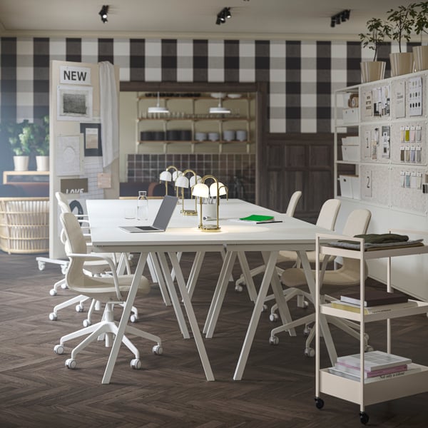 Es ist ein aktualisierter Büroraum mit vier zusammenstehenden TROTTEN Schreibtischen in Weiss zu sehen. Daran stehen LÅNGFJÄLL Konferenzstühle in Weiss/Beige.