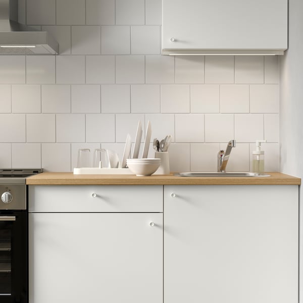 A KNOXHULT base cabinet with doors and drawers in a modern kitchen setting, featuring tiled walls and a wooden countertop.