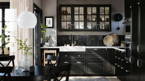 A kitchen has black BODBYN fronts with bevelled edges on the base cabinets and black BODBYN glass doors on the wall cabinets.