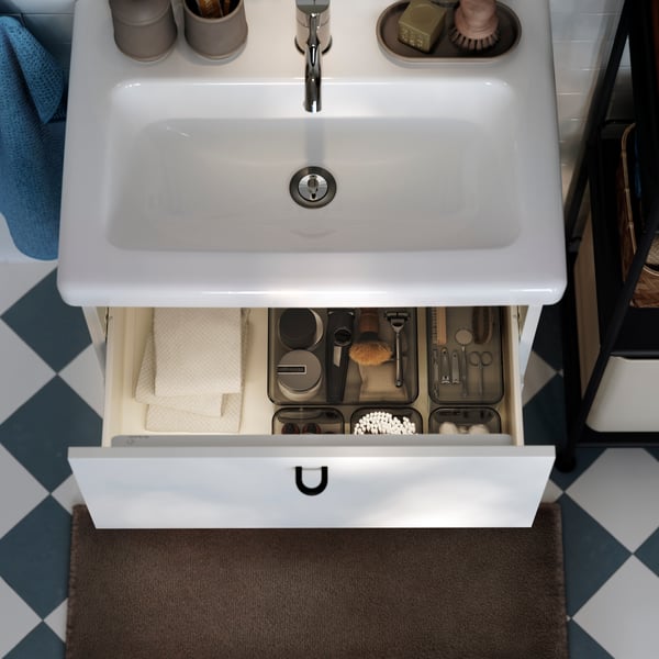 An aerial view of a white ENHET/TVÄLLEN vanity unit with basin. The top drawer is open, showing boxes with shaving products.