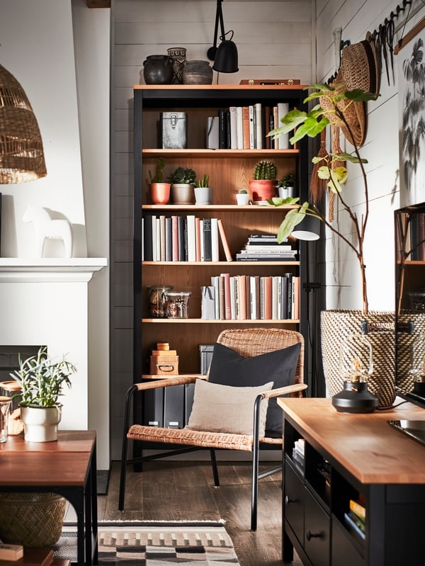 A traditional living room with a TV bench and a bookcase in black-brown/solid pine and decorative items in natural materials.
