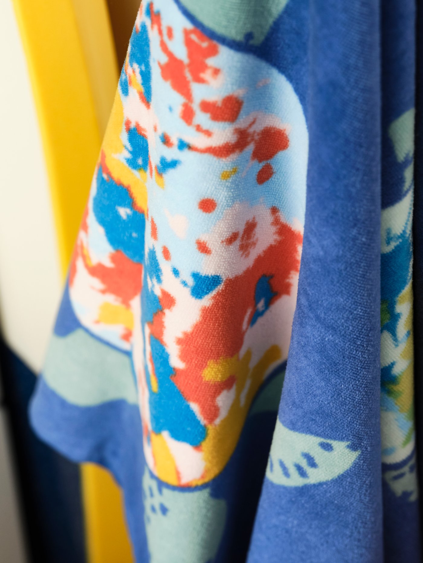 Part of a BLÅVINGAD bath towel with a multicoloured pattern that represents a turtle swimming in the ocean.