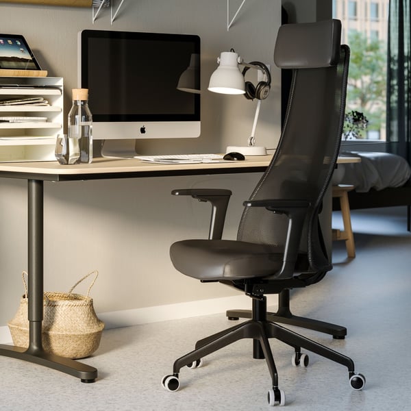 Une pièce baignée de lumière avec des affiches au mur, des rangements et un bureau blanc. Une chaise de bureau GRÖNFJÄLL noire et une lampe de bureau noire.