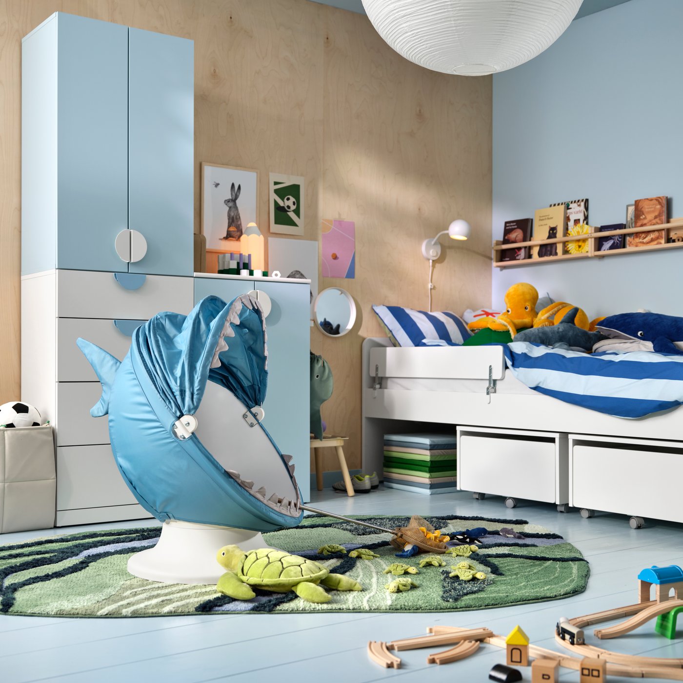 A child’s room with an IKEA PS LÖMSK swivel chair with shark slipcover, LASTARE storage, SLÄKT/NATTAPA bed, TROFAST storage.