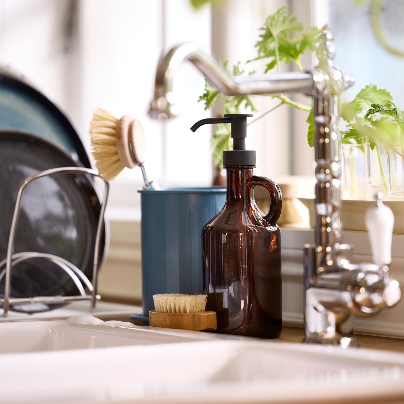 A VÄLVÅRDAD cutlery stand and a VÄLVÅRDAD soap dispenser are placed next to a sink below a kitchen window.