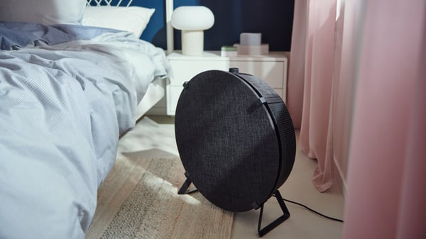 Un purificador de aire STARKVIND blanco y gris en un dormitorio.