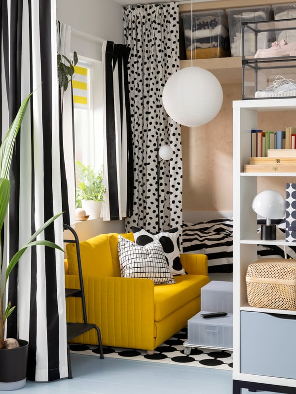 Gestreepte gordijnen hangen aan een VIDGA rail met één spoor voor een raam in een woonkamer. In de ruimte staat ook een FRIDHULT slaapbank.