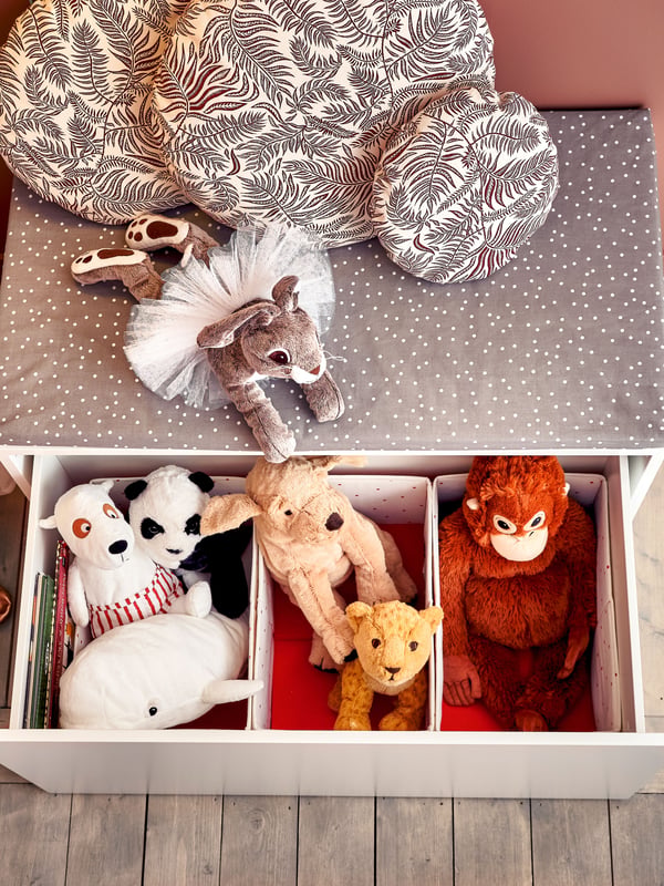 Peluches dentro de un cajón blanco organizados.
