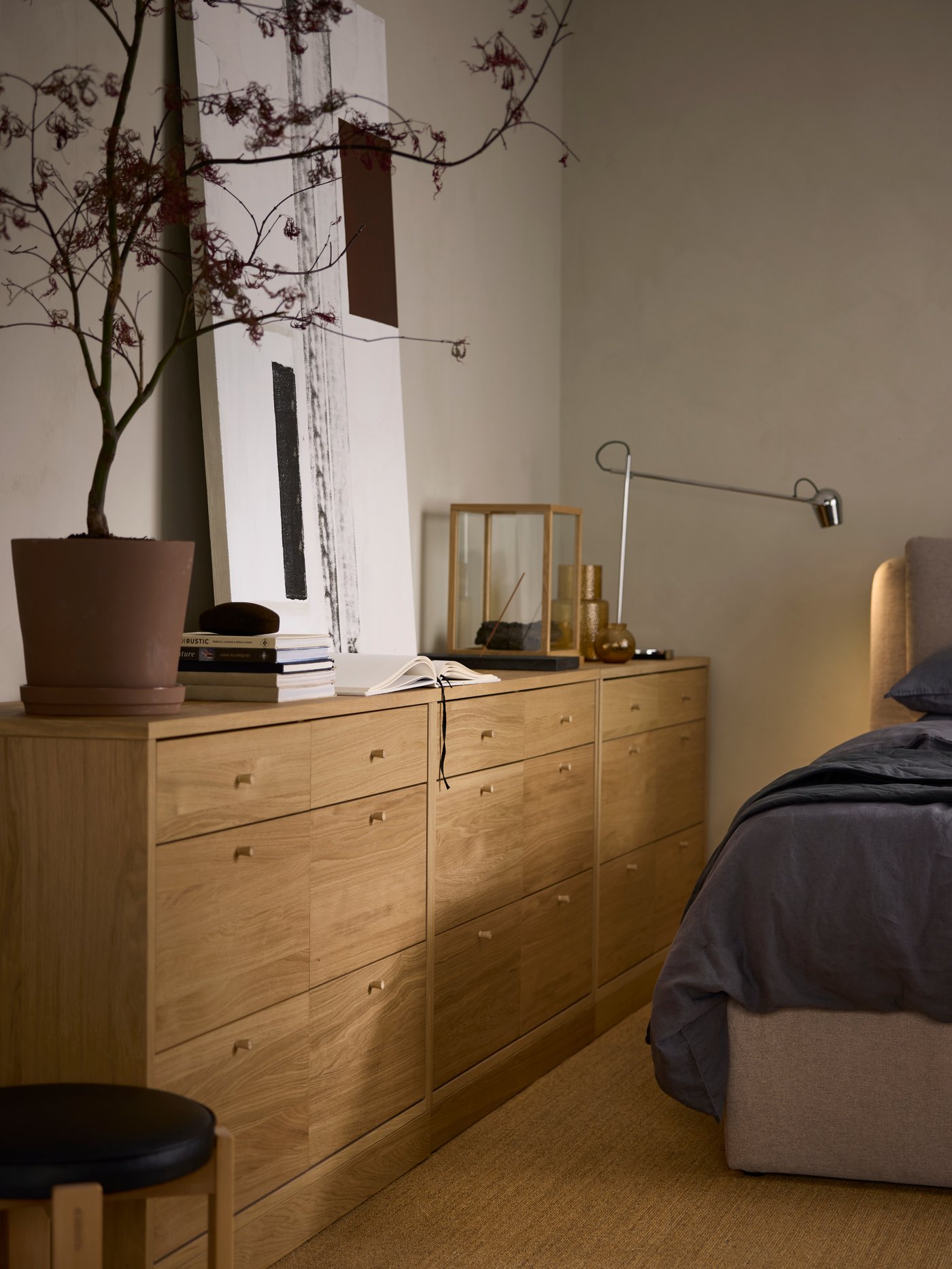 Three TONSTAD chests with 6 drawers against a beige wall with a  MODERMOLN lamp, a plant and various other objects on top.