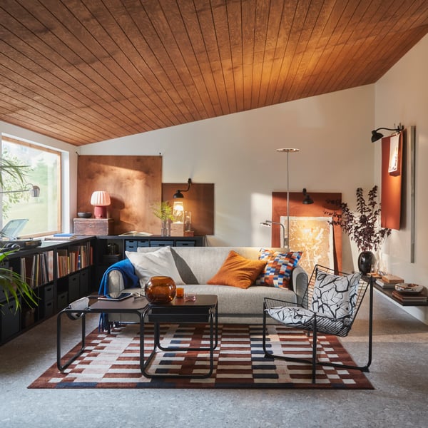 A living room features an Öreryd grey-beige SALTMYRAN 3-seat sofa placed in front of a coffee table and on a MARKBLÅMME rug.