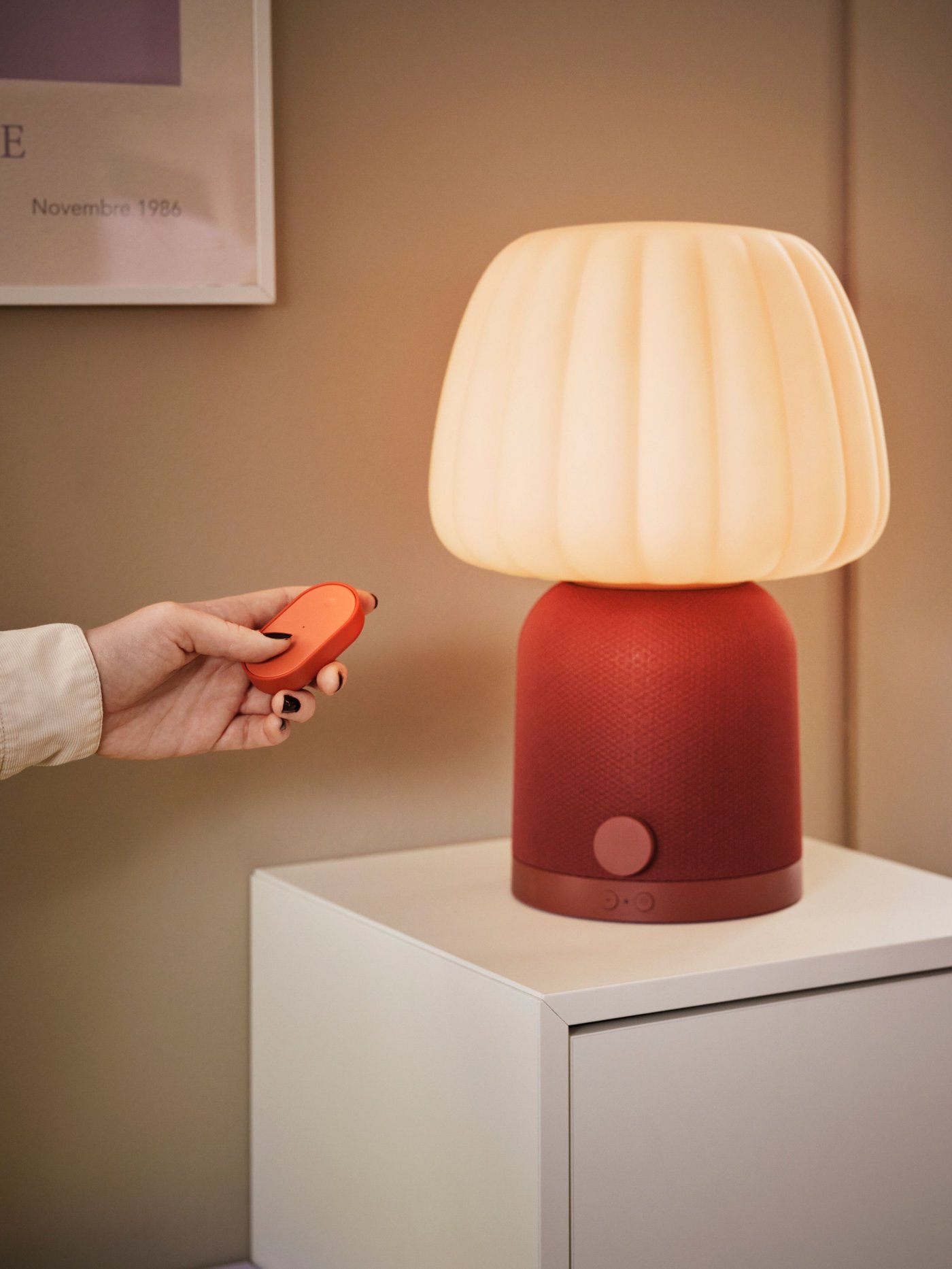 Someone is operating a KULGLASS speaker lamp with a BILRESA remote control set featuring two buttons and a multicolour function.