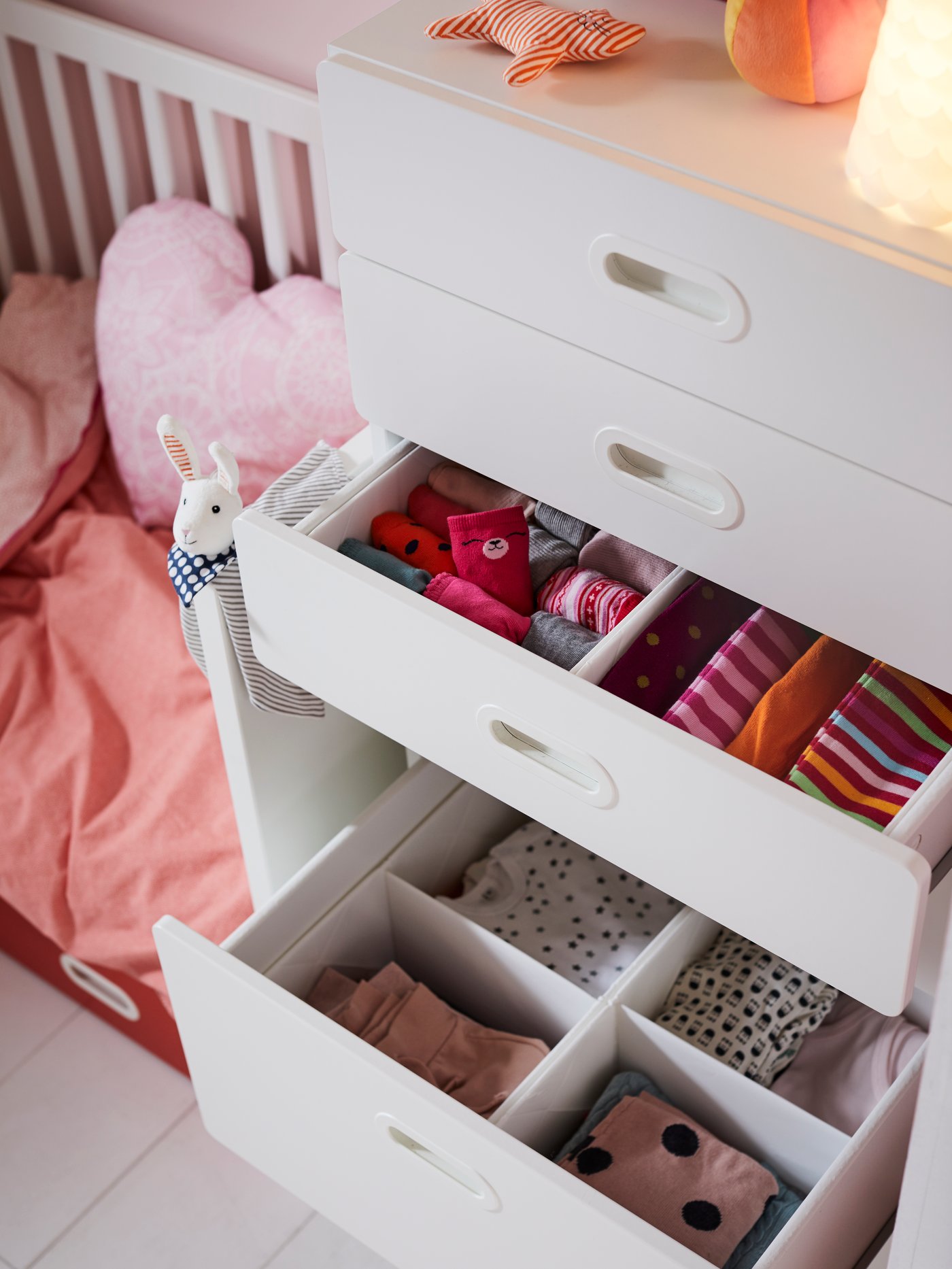 A white STUVA/FRITIDS drawer unit with open drawers containing RASSLA boxes with compartments to sort coloured clothes.