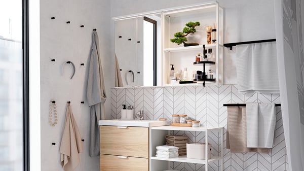 Stylish bathroom vanity with white tiles in a herringbone pattern, a wooden cabinet with sink, open shelving, and mirrored storage with lighting.