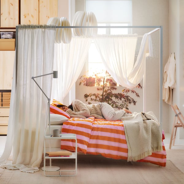 A white Luröy/Skådis white VITARNA four-poster bed frame in the bedroom
