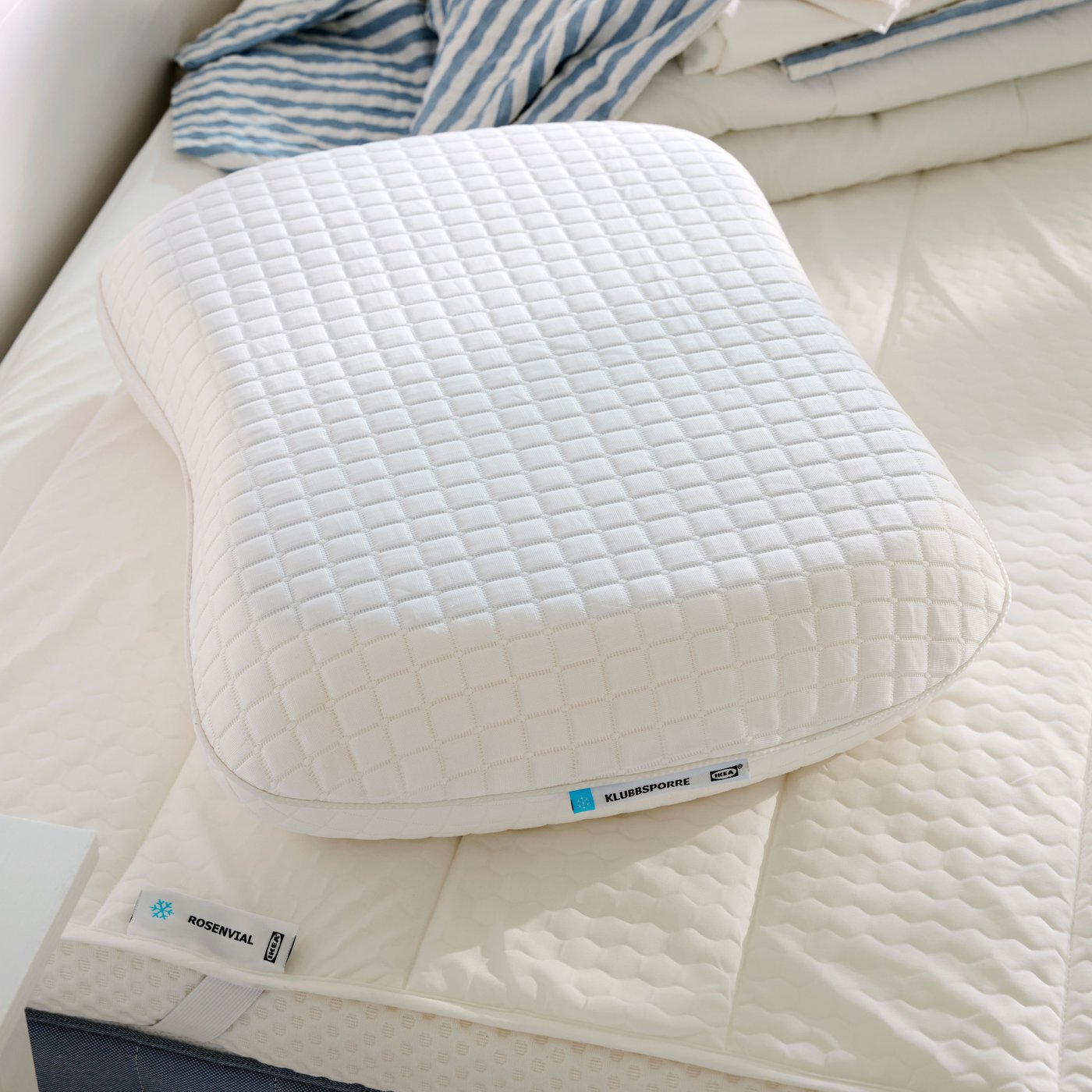 Close-up of KLUBBSPORRE ergonomic pillow on top of ROSENVIAL mattress protector, both with a cooling effect.