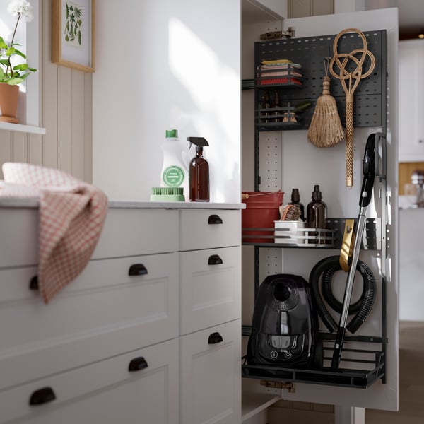 Une armoire de rangement élégante et grise comprenant des produits d’entretien, des outils et un aspirateur, le tout bien rangé pour faciliter l’accès.