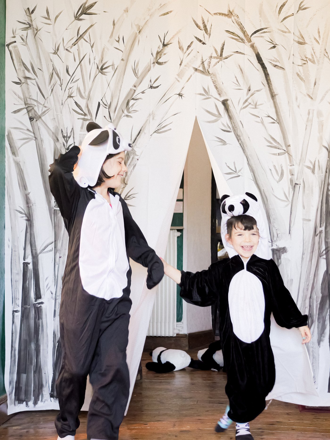 Dvoje dece u panda kostimima se poklanja ispred scenske zavese napravljene od ukrašene BJÄRSEN zavese za tuš.