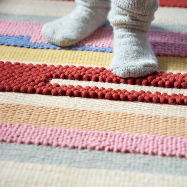 Vista en detalle de unos pies con calcetines sobre una alfombra de colores BRÖNDEN.