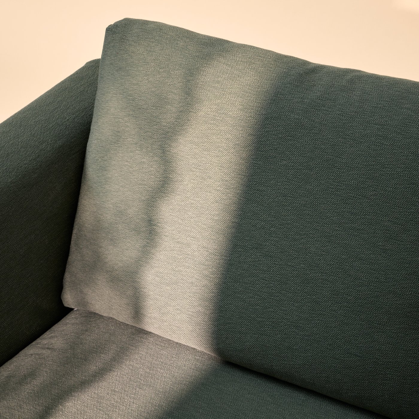 Sunlight falls softly on part of a VIMLE three-seat sofa in Knäbäck grey-green fabric, placed against a pale-yellow wall.